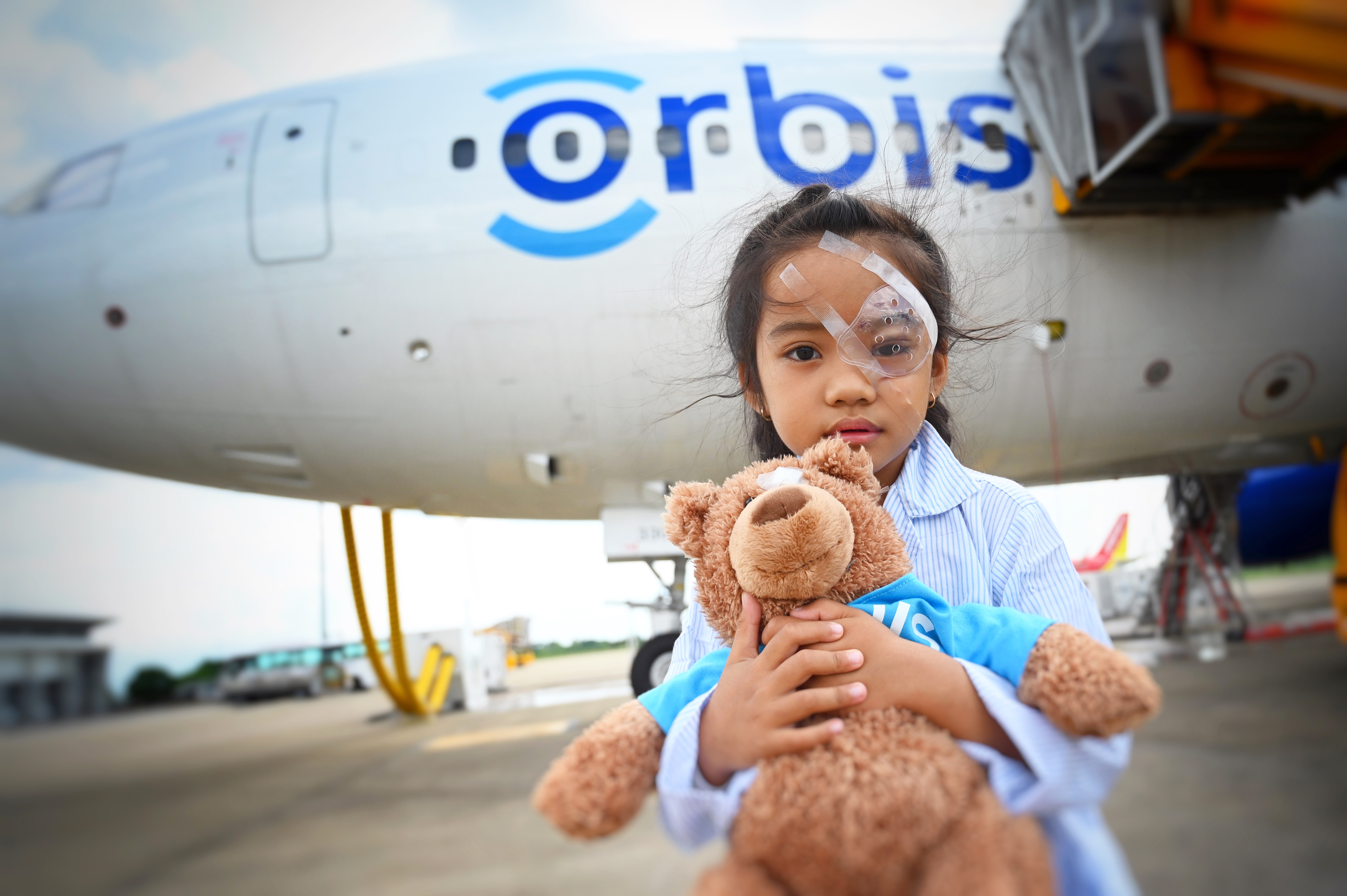 A child who received help from Orbis International standing in front of a plane